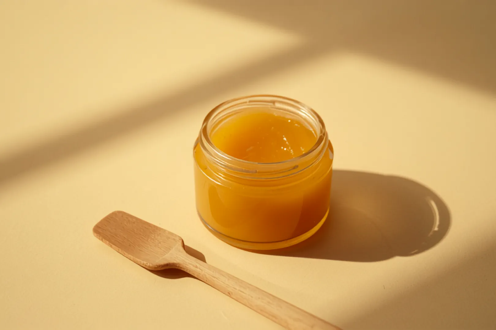 Bar glasburk med gyllenbrun beef tallow-balm och en träspatel i varmt ljus
